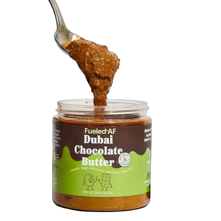 Jar of Dubai Chocolate Butter with a spoonful being lifted, on a white background