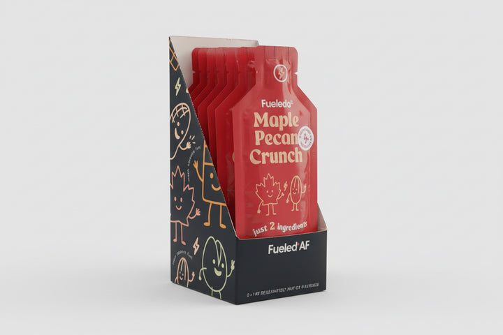 Red and black packaging of Fudgey Pecans Crunch on a dark surface