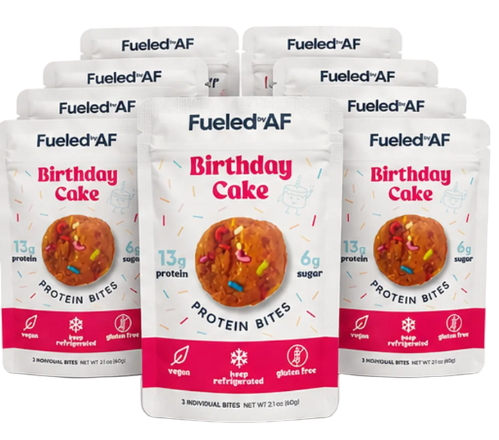 Three stand-up pouches of Fueled AF Birthday Cake Protein Bites are arranged in a fan shape on a white background, with additional pouches visible behind them.