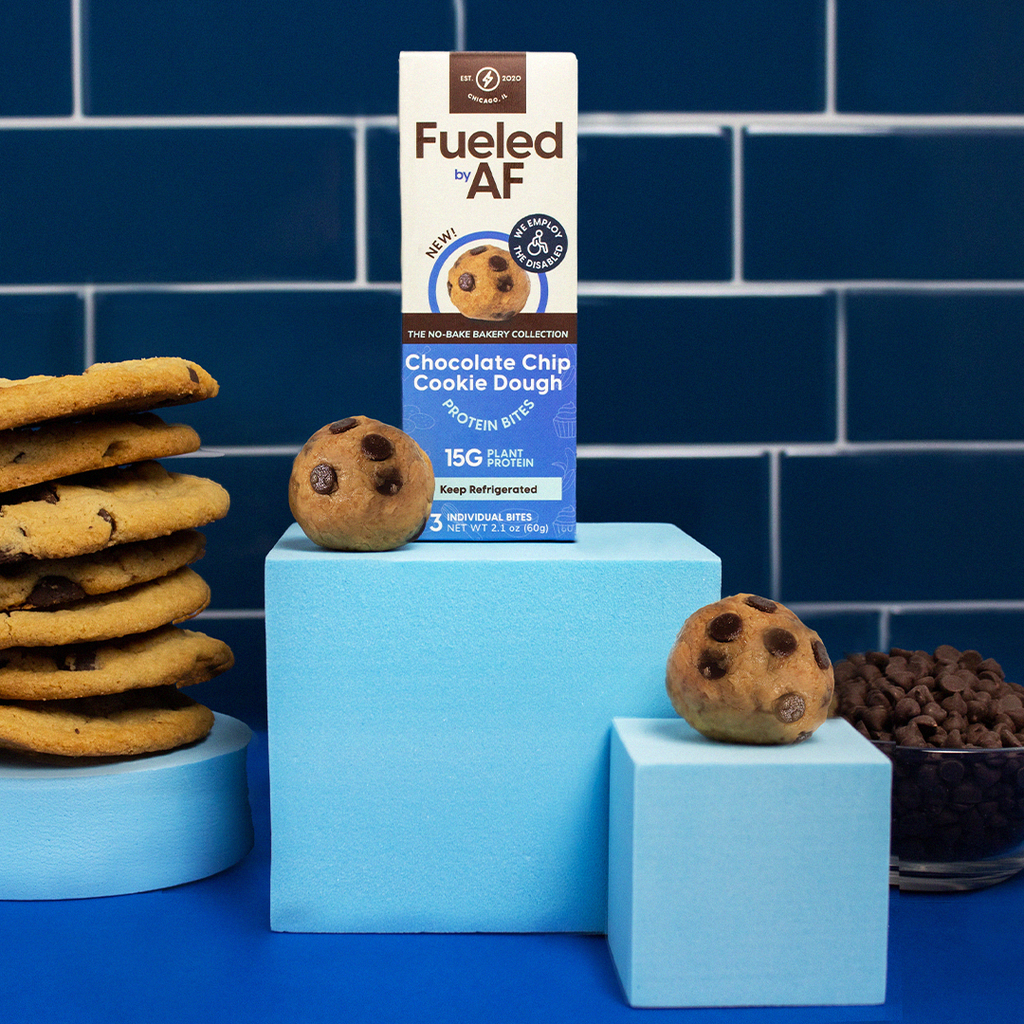 artistic product photo of chocolate chip cookie dough bites, blue back ground, freshly based chocolate chip cookies, bowl of chocolate chips, and chocolate chip cookie dough bites