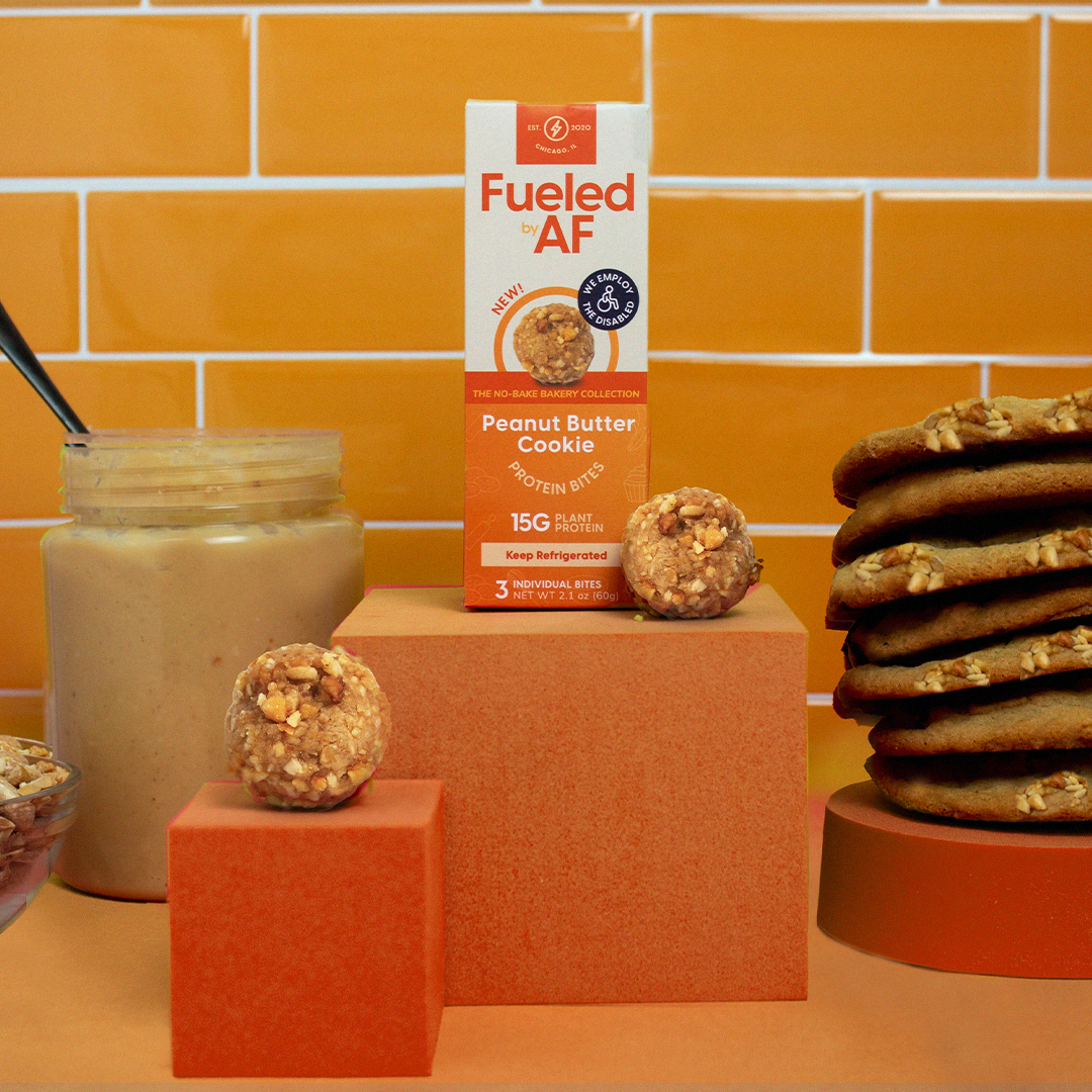 Artistic lifestyle photo of the Peanut Butter Cookie Protein Bites with a jar of peanut butter and a stack of peanut butter cookies