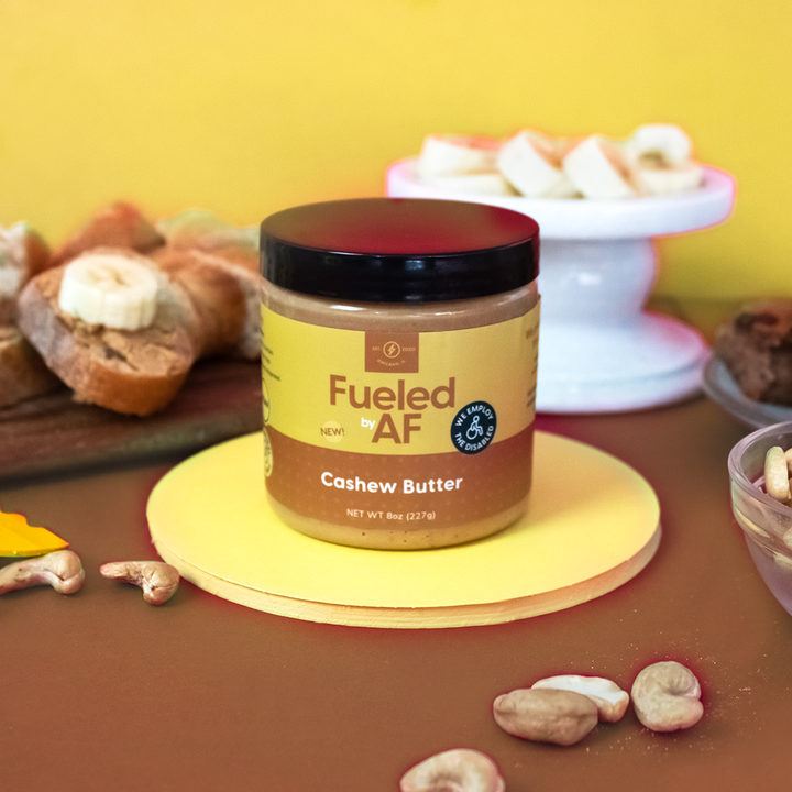 Artistic lifestyle photo of Fueled by AF cashew butter with cashews and bread and bananas